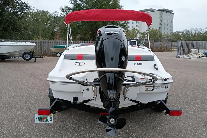 Slide: The Image of 2026 Tahoe T16 boat with red canopy and outboard motor, parked in a lot. - 3