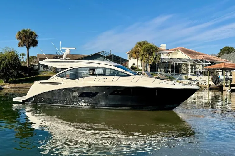 The Image of 2016 Sea Ray Sundancer 400 yacht docked by waterfront homes under clear blue sky. - 1