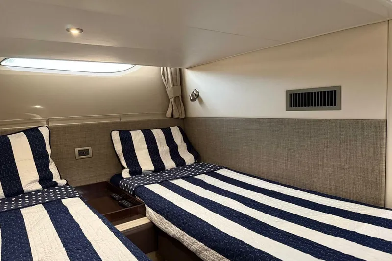 Slide: The Image of Cabin interior of 2016 Sea Ray Sundancer 400 with twin beds and striped bedding. - 9