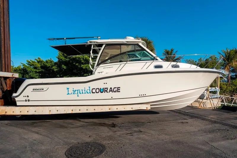 Slide: The Image of 2014 Boston Whaler 315 Conquest boat on a lift, named "Liquid Courage." - 10