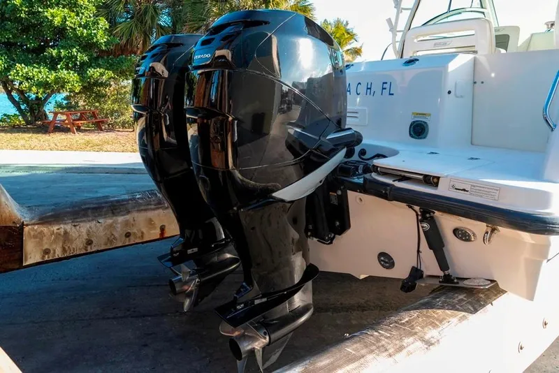 Slide: The Image of 2014 Boston Whaler 315 Conquest with dual outboard engines, docked near a scenic beach. - 11