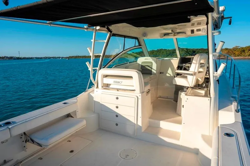 Slide: The Image of 2014 Boston Whaler 315 Conquest boat interior with seating and helm, on calm water. - 22
