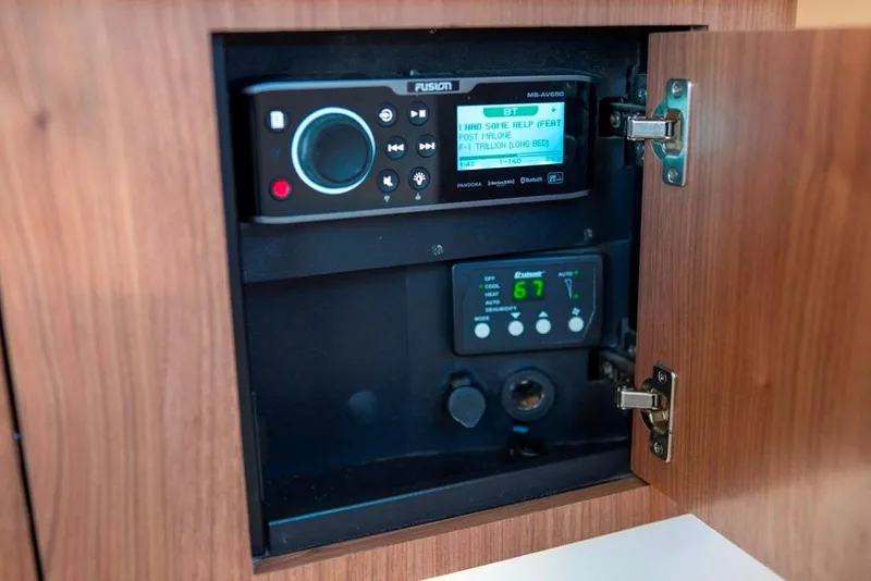 Slide: The Image of 2014 Boston Whaler 315 Conquest audio and climate control panel inside wooden cabinet. - 33