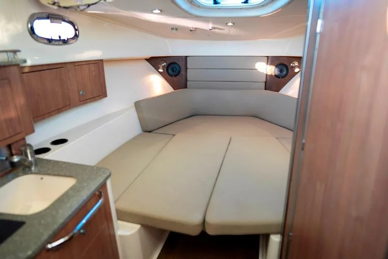 Slide: The Image of Interior cabin of 2014 Boston Whaler 315 Conquest, featuring cozy seating and wood cabinetry. - 34