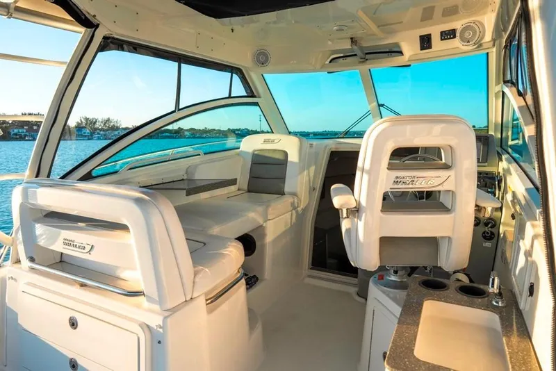 Slide: The Image of 2014 Boston Whaler 315 Conquest interior with helm and seating, overlooking serene water. - 38
