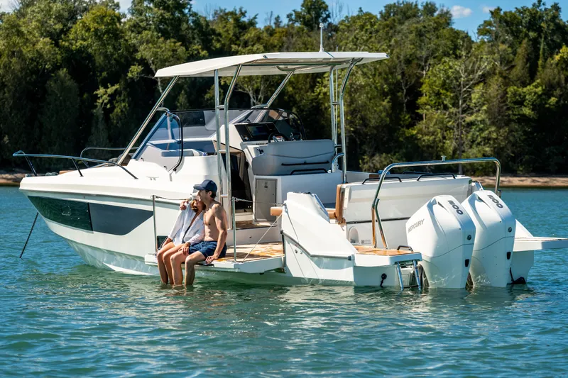 Slide: The Image of 2025 Beneteau Flyer 9 SUNdeck boat on water, with two people relaxing at the stern. - 6