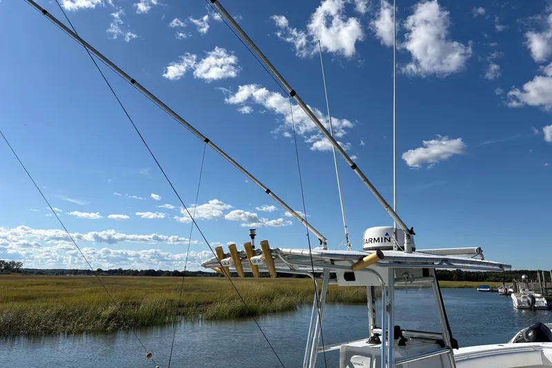 Slide: The Image of 2001 Contender 31 Open boat with fishing rods, clear sky, and marshland background. - 2