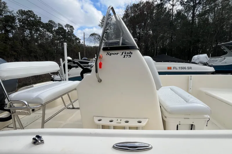 Slide: The Image of 2019 Scout 175 Sportfish boat interior with seating and console, surrounded by trees. - 8