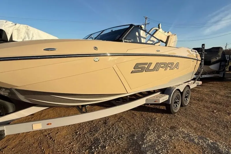 The Image of 2026 Supra SL boat on trailer, beige color, sunny day. - 1