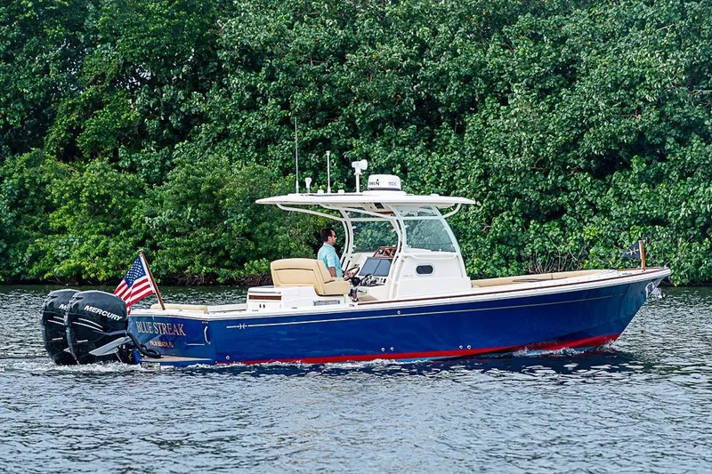 The Image of 2018 Hunt Yachts 32 Center Console cruising on water, lush greenery background. - 0