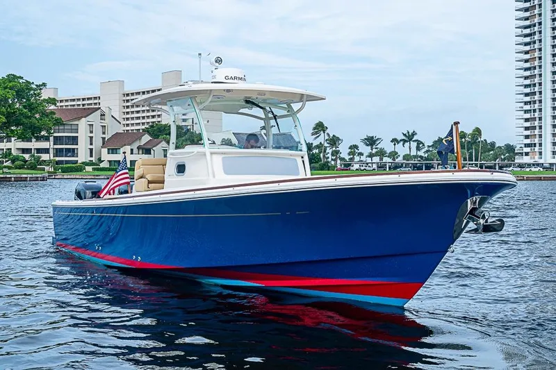 Slide: The Image of 2018 Hunt Yachts 32 Center Console on water, blue hull, American flag, urban backdrop. - 20