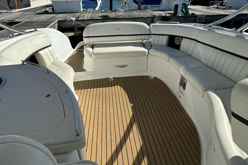 Slide: The Image of 2013 Cobalt 336 boat interior with white seating and wooden deck at a marina. - 6