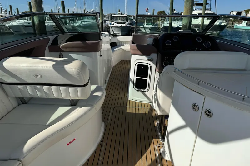 Slide: The Image of 2013 Cobalt 336 boat interior with white seating and wooden flooring at a marina. - 7