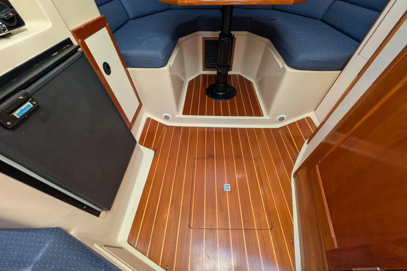 Slide: The Image of 2004 Albin 30 Family Cruiser interior with wood flooring and blue seating. - 10