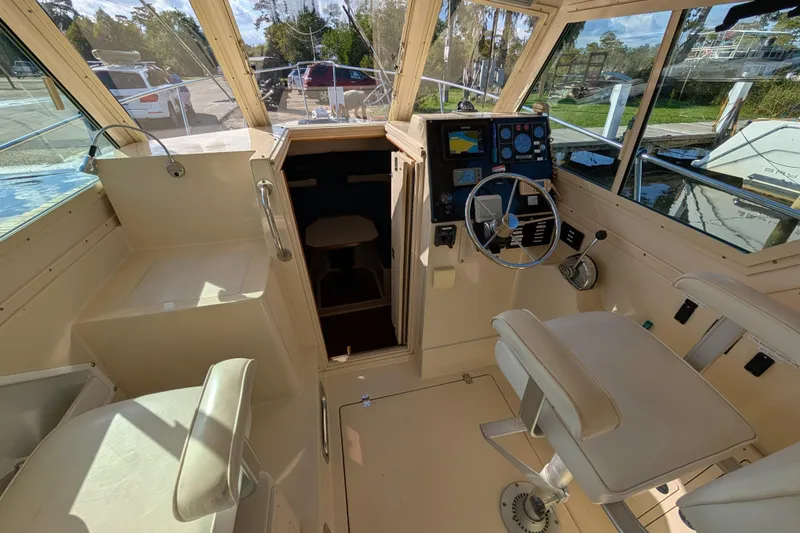 Slide: The Image of 2004 Albin 30 Family Cruiser cockpit with steering wheel, navigation controls, and seating. - 13
