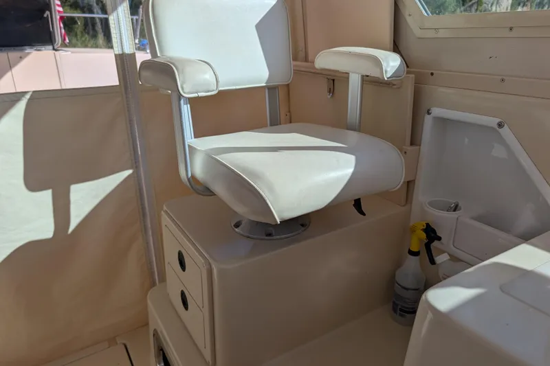 Slide: The Image of Captain's chair inside a 2004 Albin 30 Family Cruiser boat, with storage and cleaning supplies. - 20