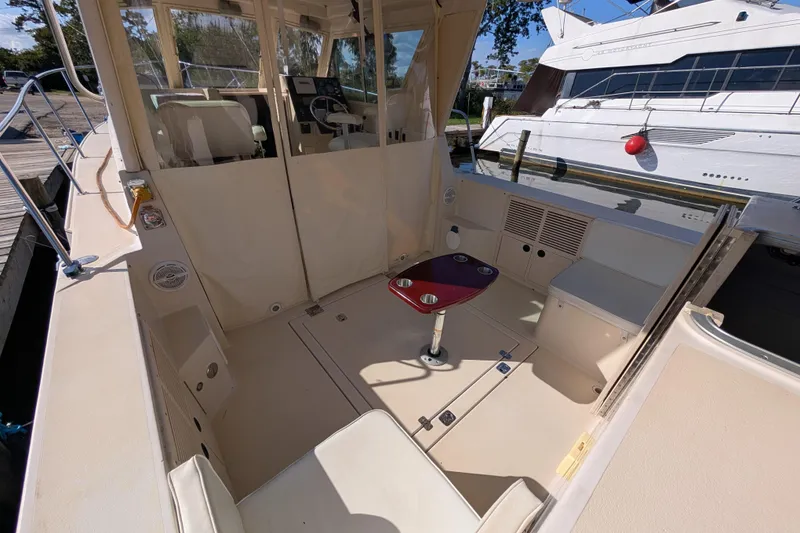 Slide: The Image of 2004 Albin 30 Family Cruiser interior with seating and table, docked beside another boat. - 22