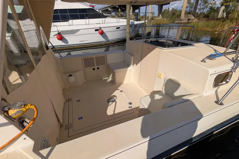Slide: The Image of 2004 Albin 30 Family Cruiser interior with seating and storage, docked near another boat. - 25