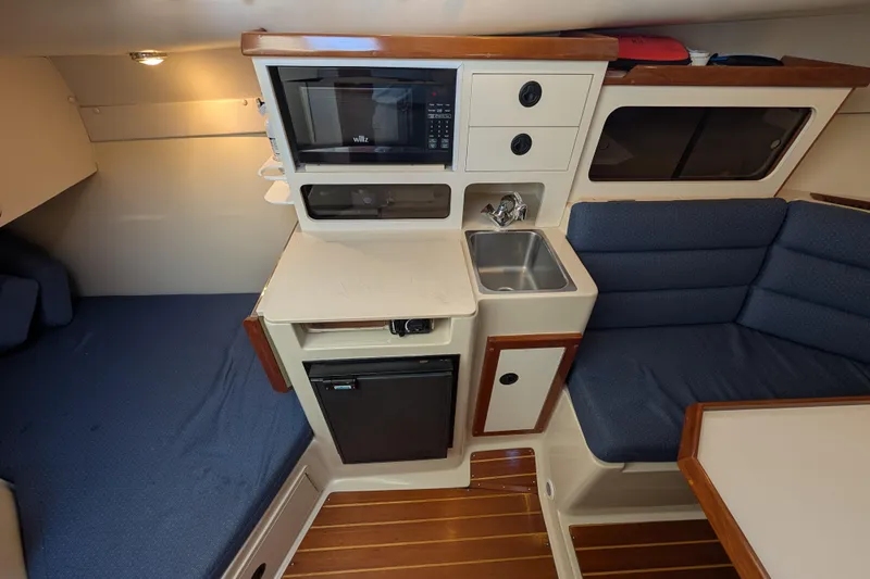 Slide: The Image of 2004 Albin 30 Family Cruiser interior with kitchenette, seating, and wood accents. - 3