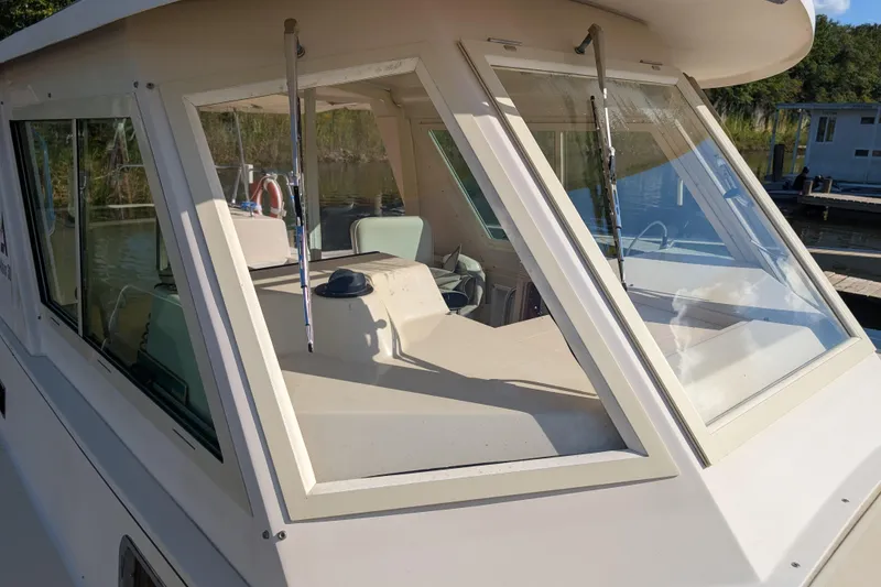 Slide: The Image of 2004 Albin 30 Family Cruiser boat with large windows, docked near a serene waterway. - 30
