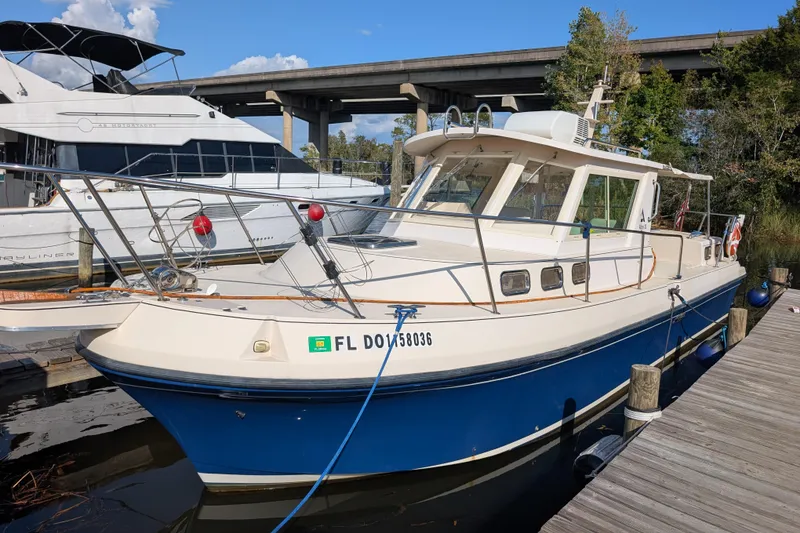 Slide: The Image of 2004 Albin 30 Family Cruiser docked, featuring a blue hull and white cabin. - 35
