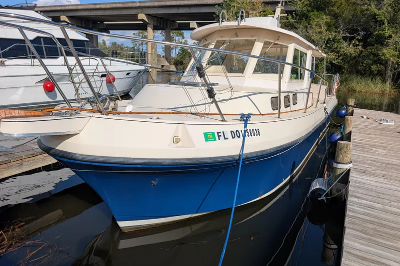 Slide: The Image of 2004 Albin 30 Family Cruiser docked, featuring a blue hull and white cabin. - 36