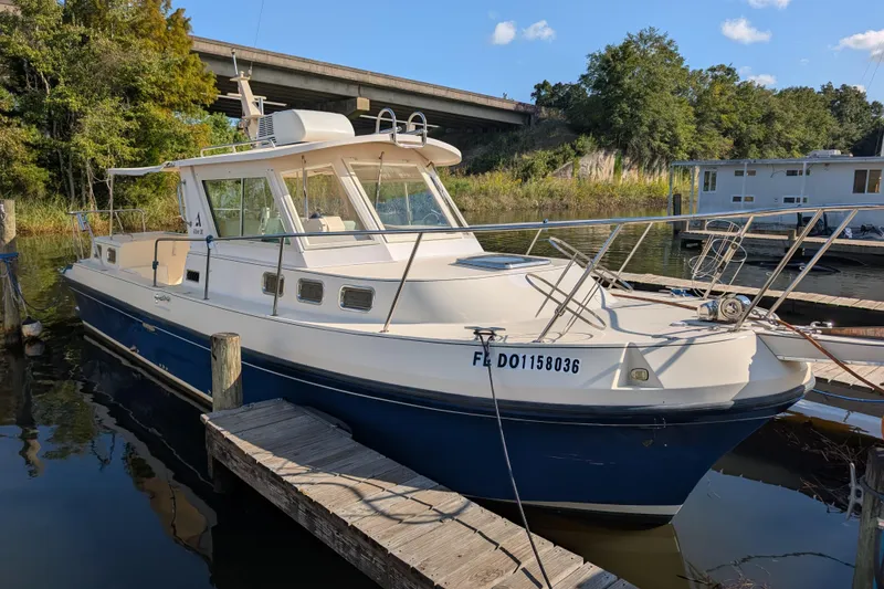 Slide: The Image of 2004 Albin 30 Family Cruiser docked by a wooden pier, surrounded by lush greenery. - 37