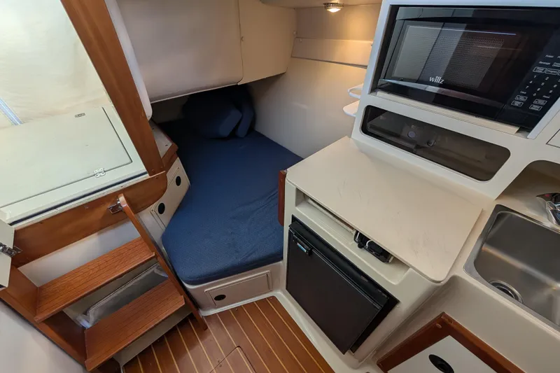 Slide: The Image of 2004 Albin 30 Family Cruiser interior with bed, microwave, fridge, and wooden steps. - 6