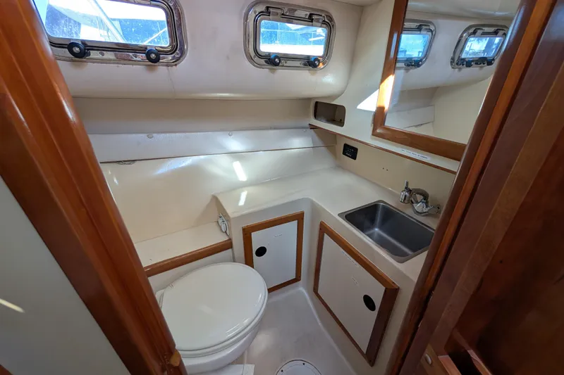 Slide: The Image of 2004 Albin 30 Family Cruiser bathroom with sink, toilet, and wooden cabinetry. - 7