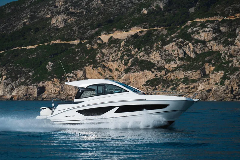Slide: The Image of 2026 Beneteau Flyer 10 Sport Top cruising on blue water near rocky coastline. - 16
