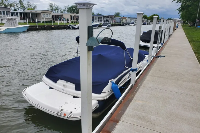 Slide: The Image of Covered 2007 Bryant 219 boat docked along a canal with nearby homes. - 9