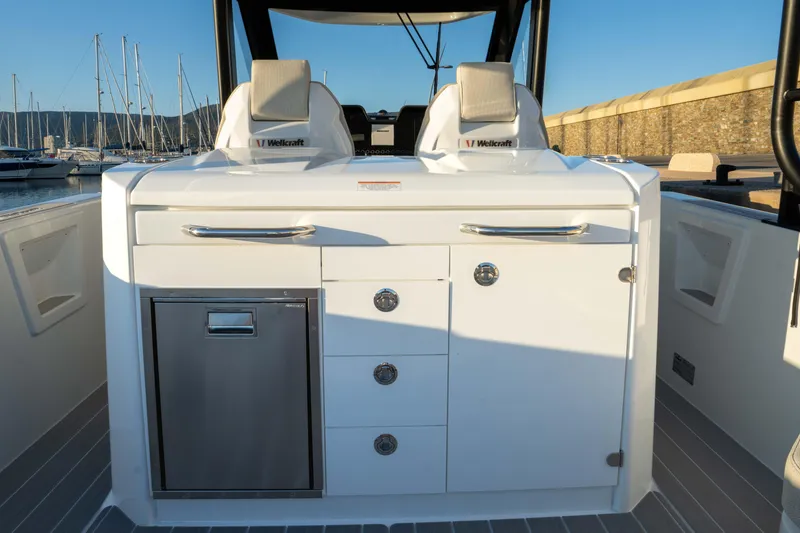 Slide: The Image of 2026 Wellcraft 28 T-Top boat interior with sleek white cabinetry and seating. - 14