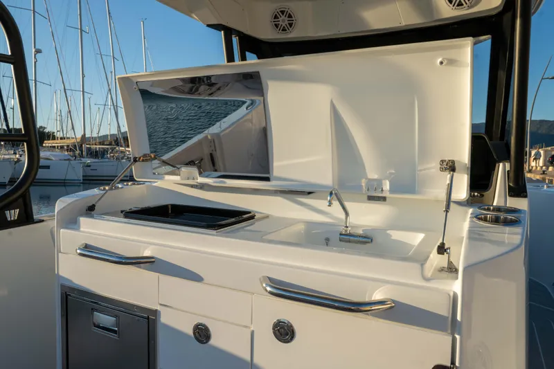 Slide: The Image of 2026 Wellcraft 28 T-Top boat galley with sink and storage, docked at marina. - 15