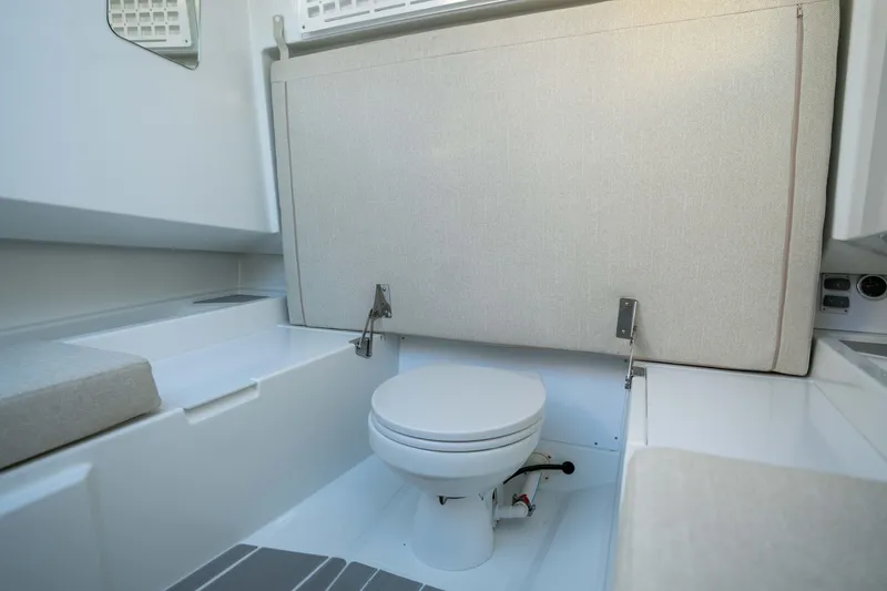 Slide: The Image of Interior of 2026 Wellcraft 28 T-Top boat featuring a compact marine toilet. - 18