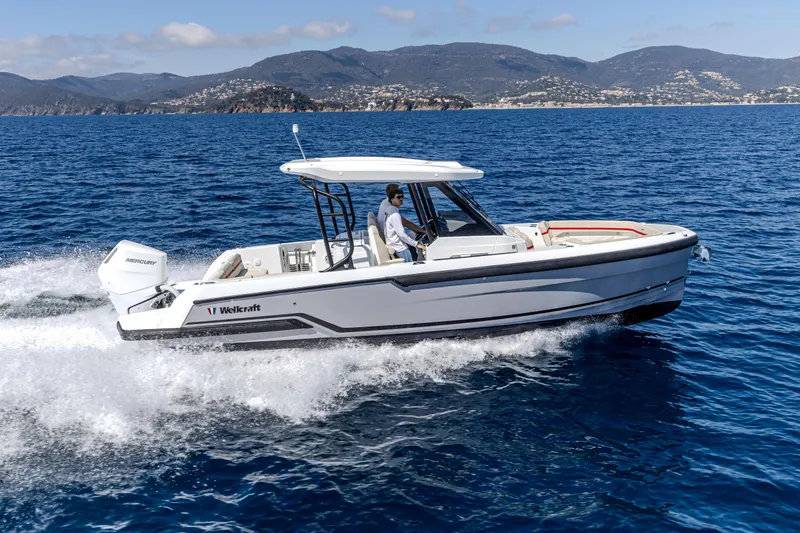 Slide: The Image of 2026 Wellcraft 28 T-Top boat cruising on open water with scenic mountain backdrop. - 31