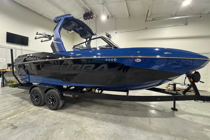Slide: The Image of 2026 Supra SL boat in a showroom, featuring sleek blue and black design on a trailer. - 7