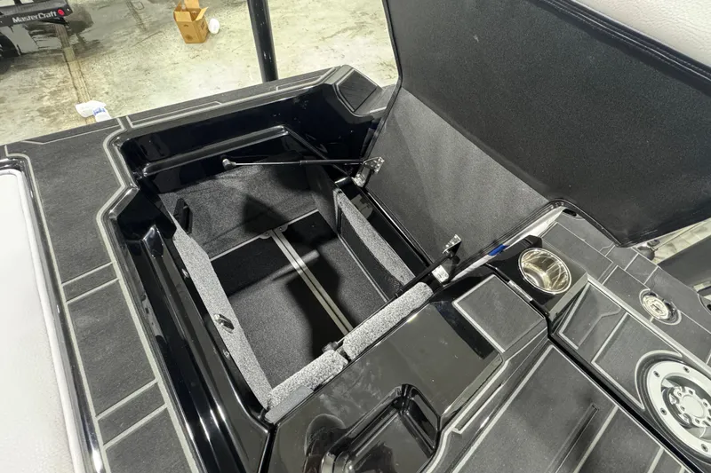 Slide: The Image of 2026 Supra SL boat storage compartment with open lid, showcasing interior design and cup holder. - 8