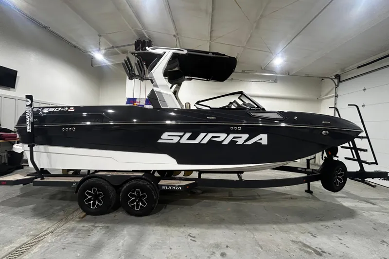 The Image of 2026 Supra SE boat in garage, black and white design, on trailer. - 2