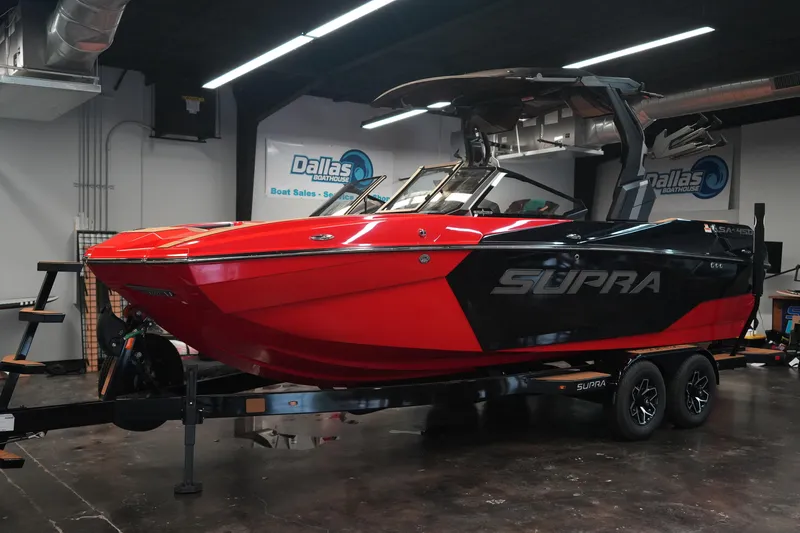 The Image of 2026 Supra SA boat in showroom, red and black design, on trailer. - 2