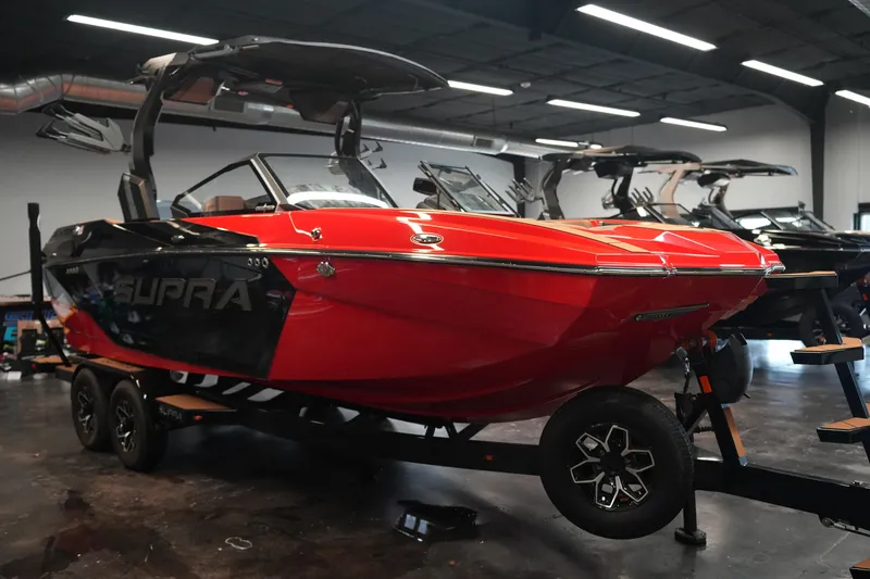 Slide: The Image of 2026 Supra SA boat in showroom, red and black design, on trailer. - 5