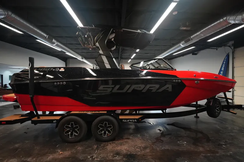Slide: The Image of 2026 Supra SA boat in showroom, red and black design, on trailer. - 6