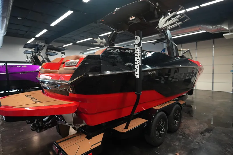 Slide: The Image of 2026 Supra SA boat in showroom, featuring sleek black and red design on trailer. - 7