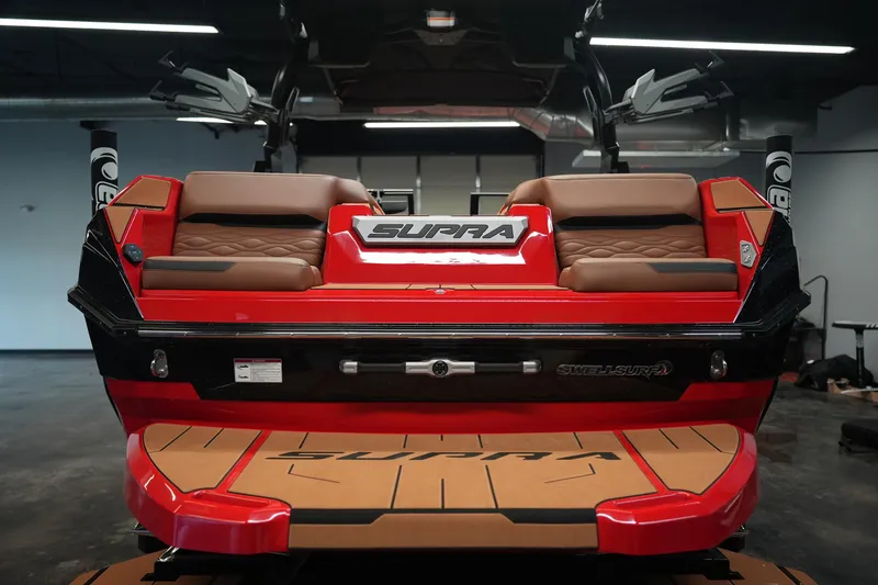 Slide: The Image of 2026 Supra SA boat rear view with red and brown seating in a showroom. - 8