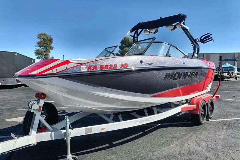 The Image of 2023 Moomba Mojo boat on trailer, red and black design, parked outdoors. - 1