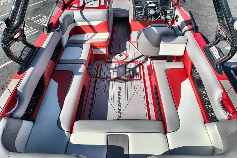 Slide: The Image of 2023 Moomba Mojo boat interior with red and gray seating, modern dashboard, and spacious layout. - 10