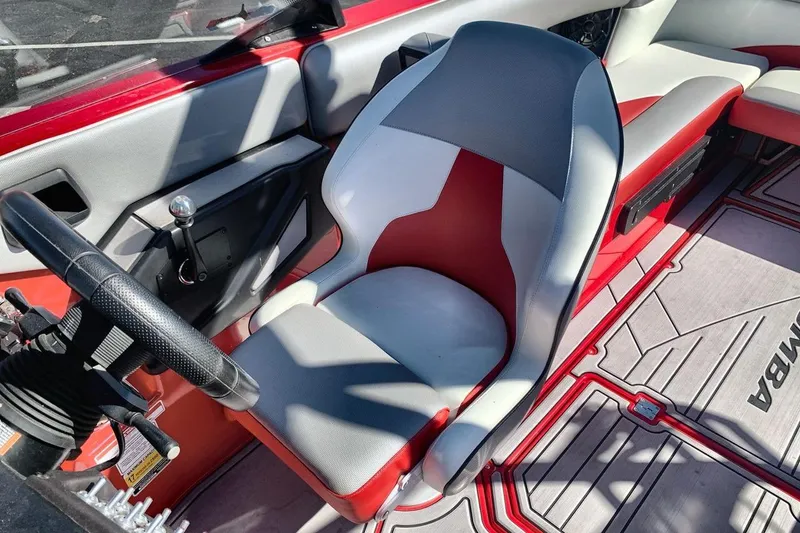 Slide: The Image of 2023 Moomba Mojo boat interior with red and gray seating and steering wheel. - 13