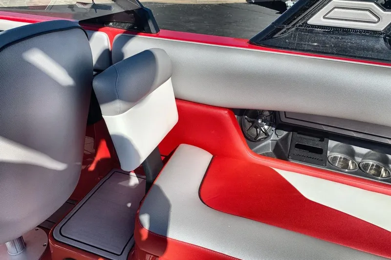 Slide: The Image of 2023 Moomba Mojo boat interior with red and gray seating, cup holders, and speaker. - 23