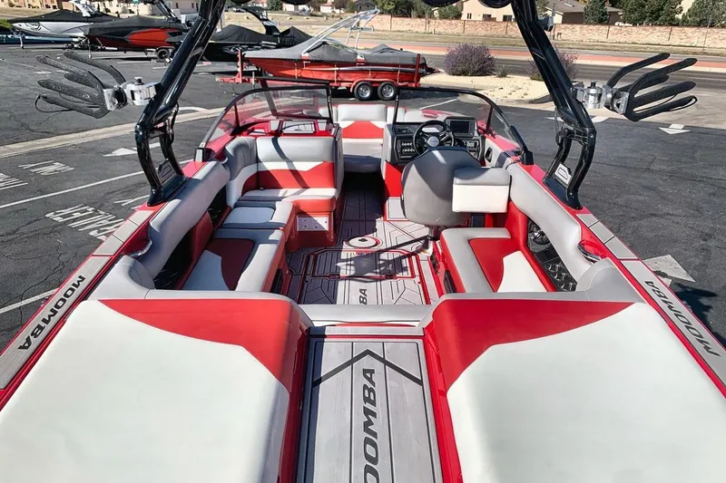 Slide: The Image of 2023 Moomba Mojo boat interior with red and gray seating, steering wheel, and wakeboard racks. - 9