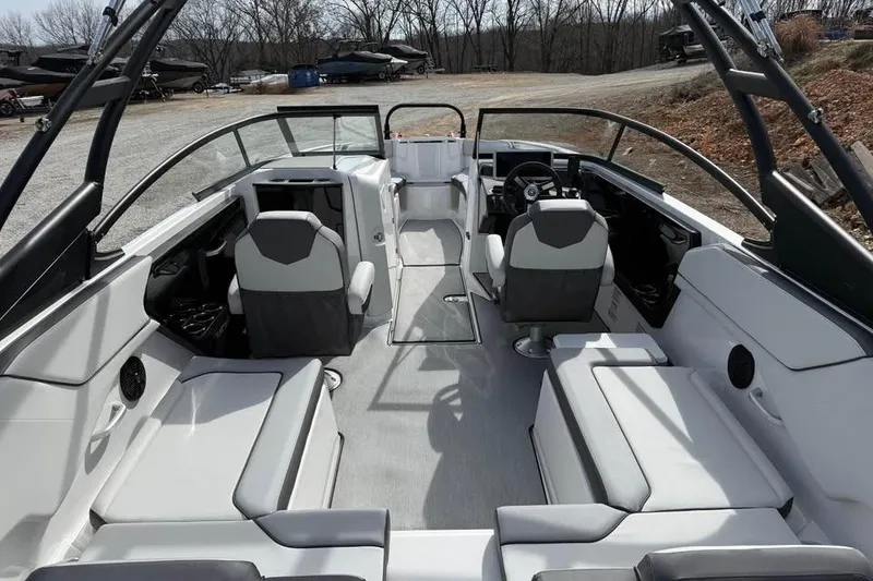 Slide: The Image of 2026 Yamaha Boats AR250 interior with modern seating and steering, parked outdoors. - 7