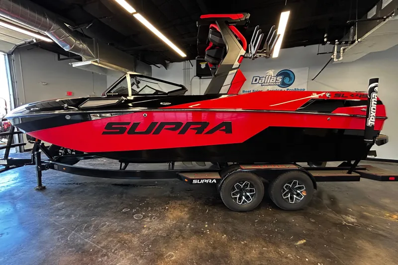 The Image of 2025 Supra SL boat in showroom, red and black design, on trailer. - 1